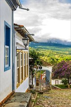 Facade of old colorful colonial houses in the historic city of Tiradentes with the forest and mountains in the background