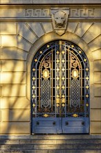 Old and imposing metal gate decorated with golden details with shadows and reflections of the late afternoon sun