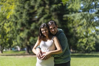 Pregnant woman posing with her partner outdoors