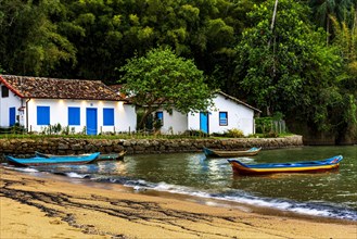 Canoes on the waters of the beach surrounded by the rainforest in Paraty at dusk