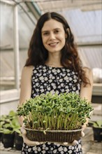 Scientist woman holding and showing the result of growing soybean seedlings in a greenhouse