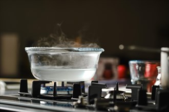 Process of boiling water in transparent casserole on gas stove