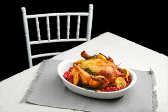 Whole chicken roasted with oranges and cranberry on the table