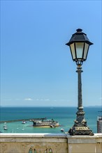 Old lamppost on a wall overlooking the sea and historic fortification in Todos os Santos Bay in Salvador