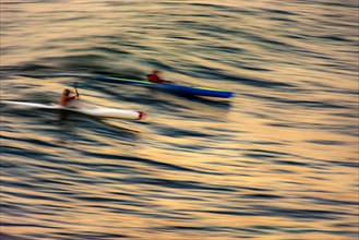 Canoeing on the wave at sunset in the sea of the city of Salvador in Bahia with blurred motion and unrecognizable people