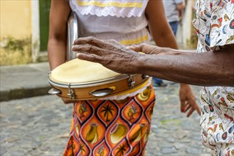 Tambourine player with a woman in typical clothes dancing in the background in the streets of the Pelourinho district in Salvador