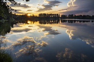 The Postfelden reservoir at sunset. Clouds are reflected in the calm water. Hoellbachtal