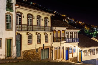 Facades of houses in colonial architecture on an old cobblestone street in the city of Ouro Preto illuminated at night