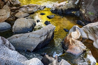 Small creek with clear and yellow waters running through the rocks of the mountains of Minas Gerais