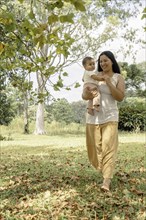 Latina mother holding a baby girl in her arms and walking in the countryside