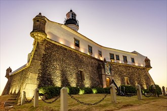 Facade of the old and historic fort and lighthouse in Barra during sunset in the city of Salvador