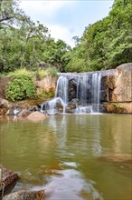 Waterfall and lake in rain forest of Moeda in Minas Gerais state on cloudy day among rocks and vegetation