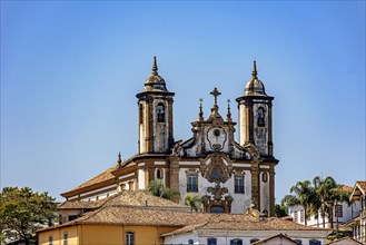 Baroque style historic church tower emerging from behind old houses in Ouro Preto city in Minas Gerais state