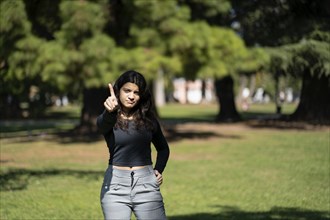 Latin teenager in a park saying no with her hand. Stop concept. Rejection concept. Non-approval concept