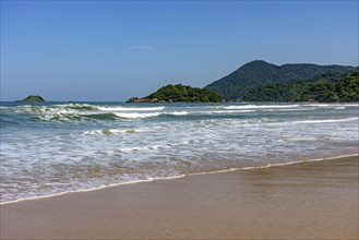 Paradise tropical beach with clean and calm waters surrounded by rainforest and hills in Bertioga coast of Sao Paulo state