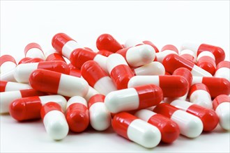 Several red and white pills of medicine on white background with free space