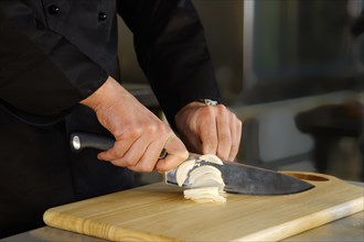 Unrecognizable man cuts onions in the kitchen