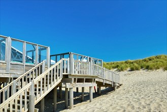 Stairs leading up to small wooden beach pavilion restaurant called 'Paal 19' on a summer day on island Texel in Netherlands