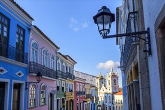 Old facades of colorful colonial-style houses and a tower of an old baroque church in Pelourinho