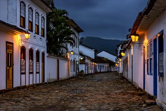 Streets and houses of the historic city of Paraty in the state of Rio de Janeiro illuminated at dusk with the mountains in the background