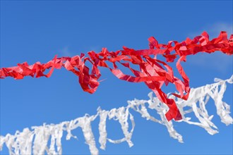 Decorative vivid red and white ribbons prepared for a religious festival in the city of Lavras Novas in Minas Gerais swaying in the wind with blue sky in background