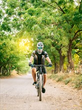 Professional cyclist on a dirt road. Fat cyclist on a dirt road surrounded by trees