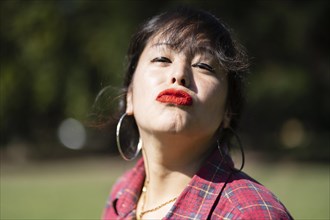 Portrait of andean woman posing in a park. Model striking a pose in a park. Woman blowing a kiss