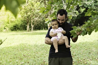 Father holding baby girl surrounded by nature. Father's Day Concept