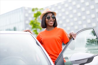 Ready to go: young black woman in summer outfit and sunglasses opening car door