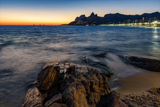 Sunset during the summer with city lights on at Ipanema beach in Rio de Janeiro
