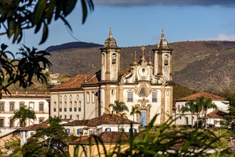 One of the main historic churches in the city of Ouro Preto seen through the vegetation with the mountains in the background