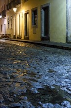 Streets of the Pelourinho district with its facade of colonial houses and cobblestones wet by rain illuminated at night