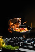 Flambering wok ingredients in a frying pan