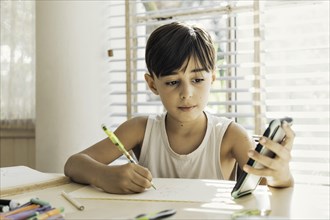 Child sitting at home with pen in hand drawing and coloring. Process of learning and the creative development of children