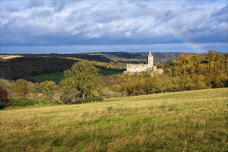 Rudelsburg castle ruins in the Saale valley in autumn under dark clouds and rainbow