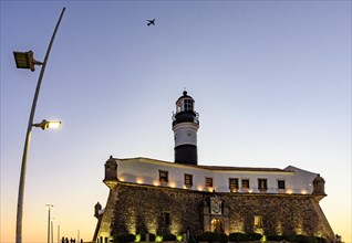 Facade of the old and historic fort and lighthouse in Barra beach during sunset in the city of Salvador