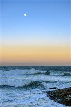 Moon over the sea and waves during sunset at Ipanema beach in Rio de Janeiro