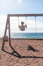 A woman on vacation swinging on a swing on the beach of the island of El Hierro. Canary Islands