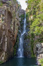 Beautiful waterfall called Veu da Noiva between moss covered rocks and the vegetation of an area with nature preserved in the state of Minas Gerais