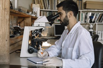 Male scientist looking under microscope