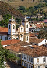 One of the many historic churches in baroque and colonial style from the 18th century amid the houses and roofs of the city Ouro Preto in Minas Gerais