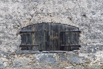 Closed window with wooden shutters on an old farmhouse