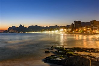 Ipanema beach with beautiful skyline and sunset. City lights and buildins araoud the ocean