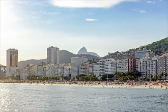 Sunny day at Copacabana Beach in Rio De Janeiro with the slum and the statue of Christ the Redeemer in the background