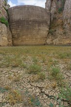 This striking photograph depicts a reservoir dam during a severe drought. The reservoir