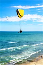 Paraglider flight over the beach in the city of Torres in Rio Grande do Sul with the sea and horizon in the background