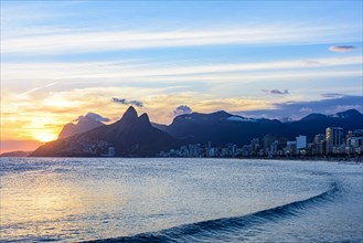 Sunset behind the mountains of the city of Rio de Janeiro on Ipanema beach