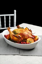 Whole chicken baked with oranges and cranberry in oven