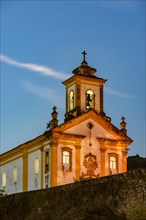 Old and historic 18th century church with its facade illuminated at dusk in the city of Ouro Preto