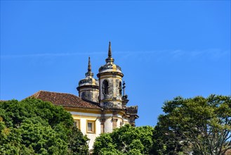 Side view of historic church in baroque and colonial style from the 18th century amid the hills and vegetation of the city Ouro Preto in Minas Gerais